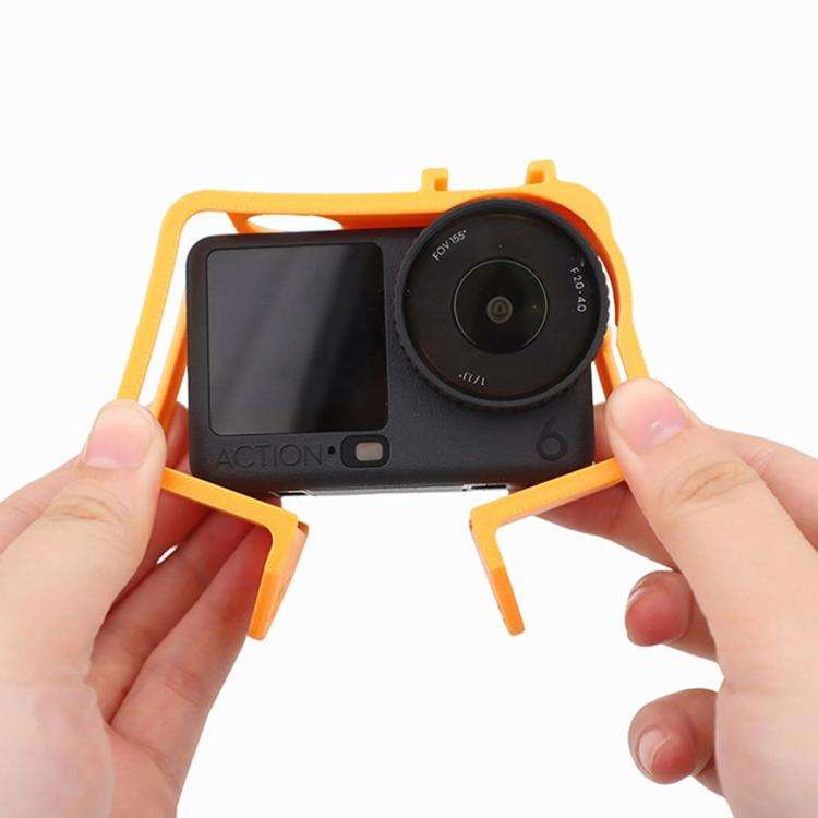 Person sätter på orange Cold Shoe Cage Expansion Adapter Frame på actionkamera, visar enkel installation och passform.